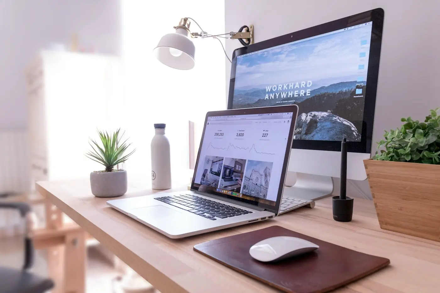A tidy desk with an iMac and a laptop showing website designs